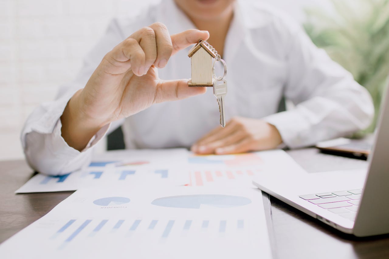Real estate digital marketing strategies 2025 – agent holding house key over charts and laptop